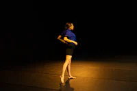 a woman in a blue shirt standing on a dark floor