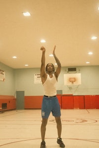a man in a gym with his arms raised in the air