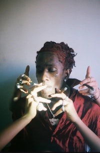a man with dreadlocks is smoking a cigarette