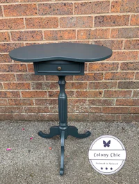 a small grey table with a drawer on it