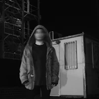 a man in a hoodie standing in front of a building at night