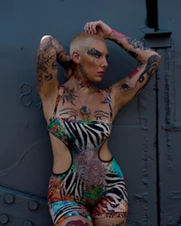 a woman in a zebra print bodysuit leaning against a wall