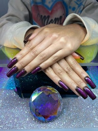 a woman with purple nails and a crystal on a table