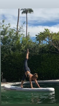 a woman doing yoga on a stand up paddle board