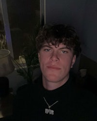 a young man wearing a black turtleneck and a necklace