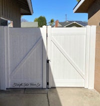 a white fence with a white gate in front of it