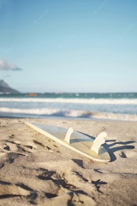 a surfboard lying on the sand near the ocean