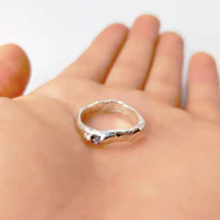 a person's hand holding a silver ring