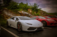 a white lamborghini and a red porsche parked in a parking lot
