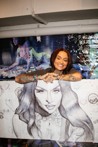 a woman holding a drawing of a tattooed woman