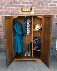 a wooden wardrobe with coats, boots and hats