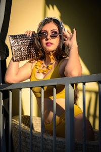 a woman in a yellow bikini posing on a balcony