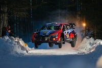 a rally car is flying through the snow at night