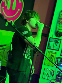 a man singing into a microphone in front of a green screen