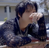 a young man leaning against a fence
