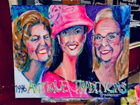 a painting of three women on a easel