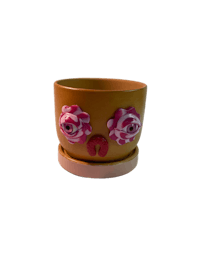 a yellow flower pot with pink roses on it