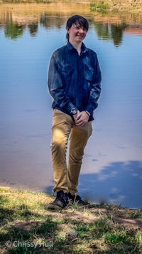 a young man standing next to a body of water