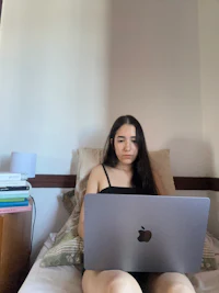a woman sitting on a bed with a laptop