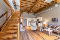 a living room with wood floors and a staircase