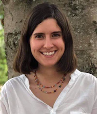 a woman smiling in front of a tree