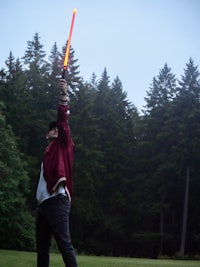 a man is holding a light saber in the air