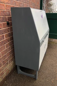 a grey cabinet sitting outside of a brick wall