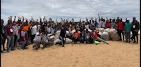 a group of people posing for a photo on the beach