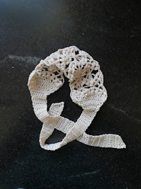 a white crocheted headband on a black surface