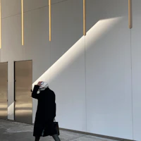 a woman walks past a building with white walls