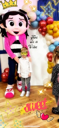 a child is standing next to a mascot dressed as a princess