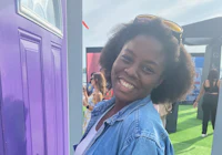 a woman smiling in front of a purple door