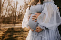 a pregnant woman in a blue dress is holding her husband's hand