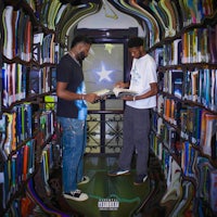two men standing in front of a book shelf