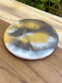 a yellow and white ceramic coaster on a wooden table