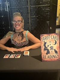 a woman sitting at a table with a deck of cards