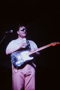 a man holding a guitar in front of a microphone