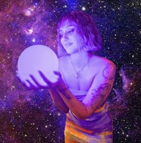 a woman holding a purple crystal ball in front of a starry sky