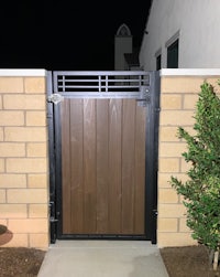 a wooden gate at night with a plant in front of it