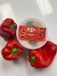two red peppers next to a container of cheese