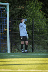 a woman standing on a soccer field holding a water bottle