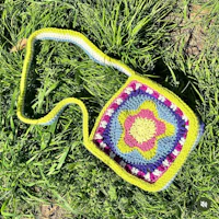 a crocheted bag laying in the grass