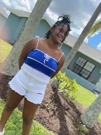 a young girl wearing white shorts and a blue crochet top