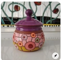 a purple and yellow ceramic jar with a lid