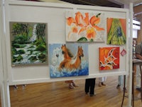 a group of people standing in front of a display of paintings