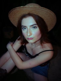 a woman in a hat sitting on a rock