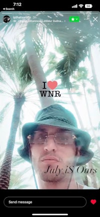a man in a hat is standing in front of a palm tree