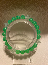 a green glass bead bracelet on a white surface
