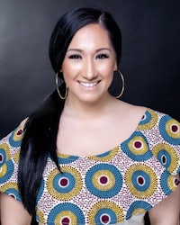 a woman in an african print top smiles for the camera