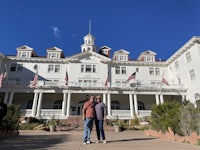 two people standing in front of a large white building